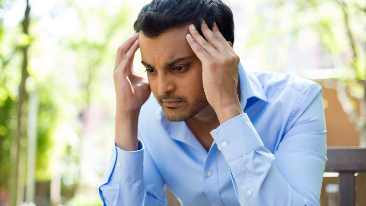 7 Reasons To Skip the Trip and Plan a Staycation Instead 5 Closeup portrait, stressed young business man, hands on head with bad headache, isolated background of trees outside. Negative human emotion facial expression feelings.