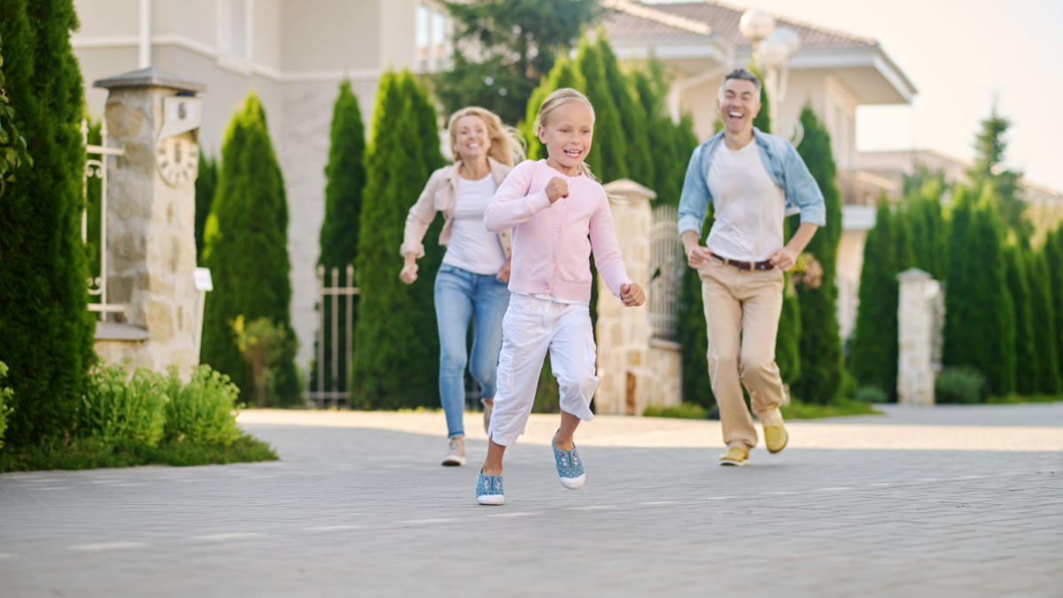 Cheerful running little girl and catching up parents