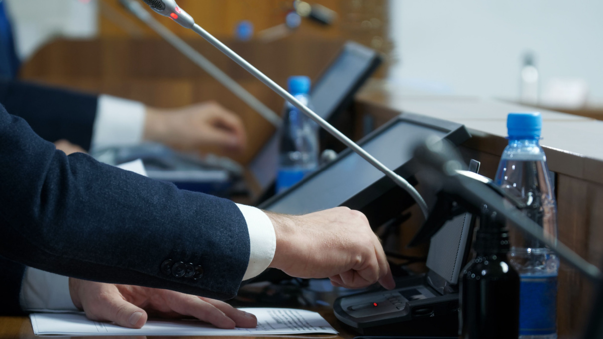 The politician's hand is extended to the voting device. The concept of making a decision and adopting amendments to legislation.