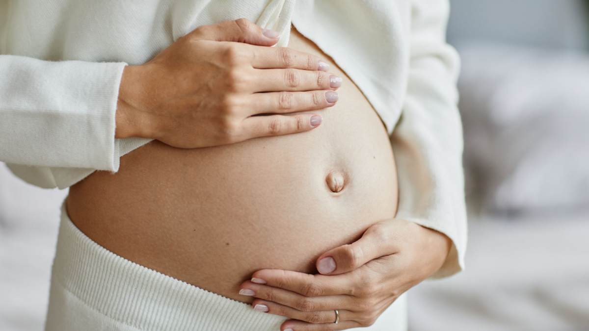 Close-up of young pregnant woman touching her belly and caring about her health