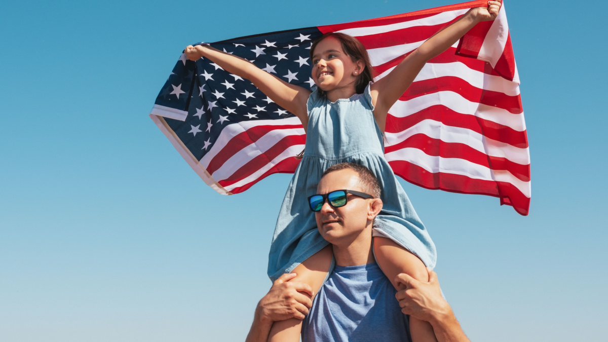Happy family father and child with usa flag enjoy nature on sky background.