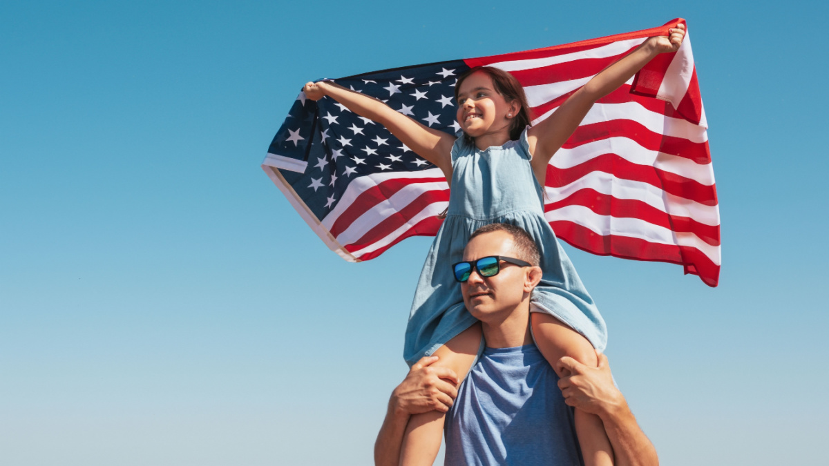 Happy family father and child with usa flag enjoy nature on sky background.