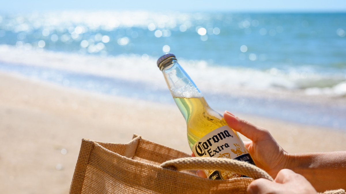  A girl on the beach takes out a bottle of Corona Extra beer from her bag.