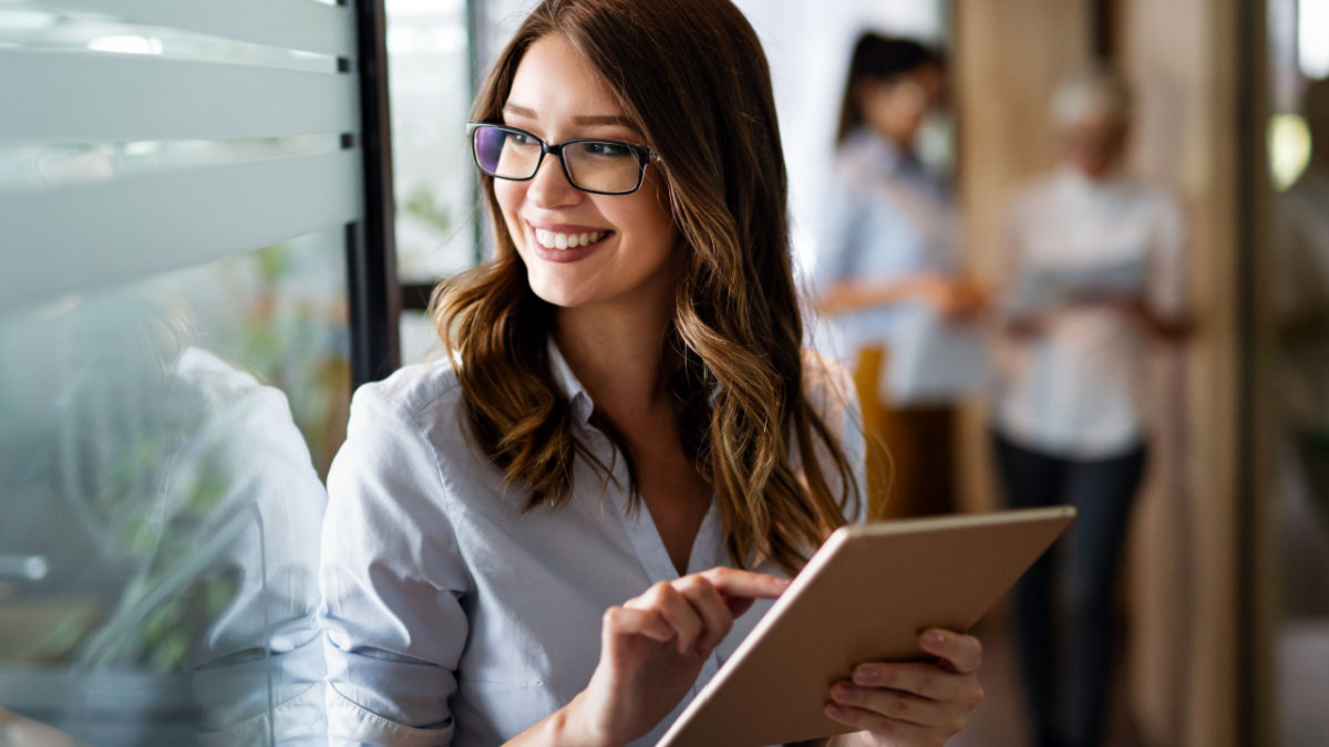 Young happy business woman working with tablet in corporate office.