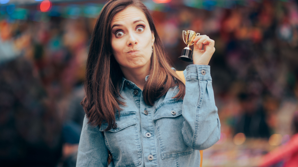 Funny Woman Winning a Small Trophy at Funfair Contest. Sore loser receiving a participation consolation prize