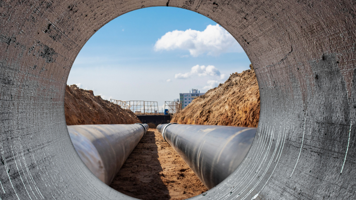 Water pipes for drinking water supply lie on the construction site. View from a large concrete pipe.