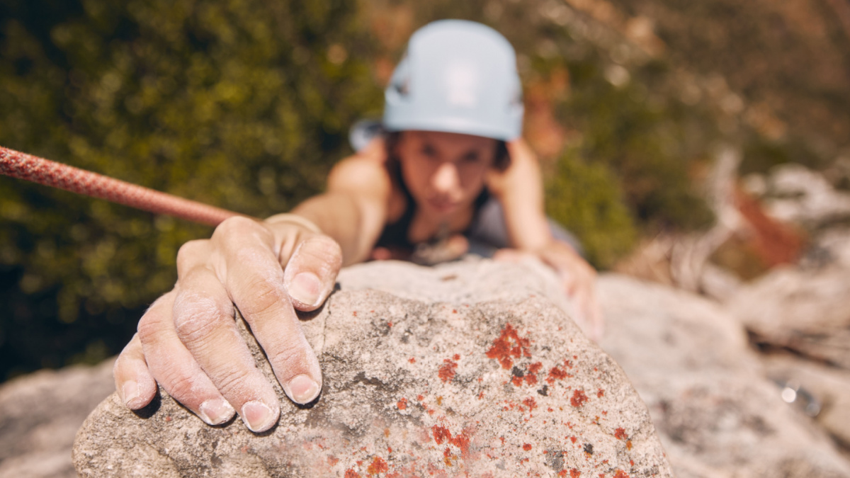 Woman, hand and rock climbing with rope on mountain, hill or remote hiking for workout, training and exercise.