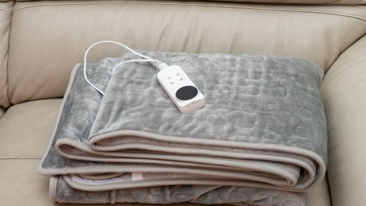 folded electric blanket with controller on a sofa.