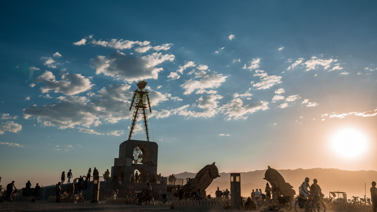 Beautiful desert with art objects at sunrise. Beautiful nature festival with people riding bicycles. Burning Man festival.