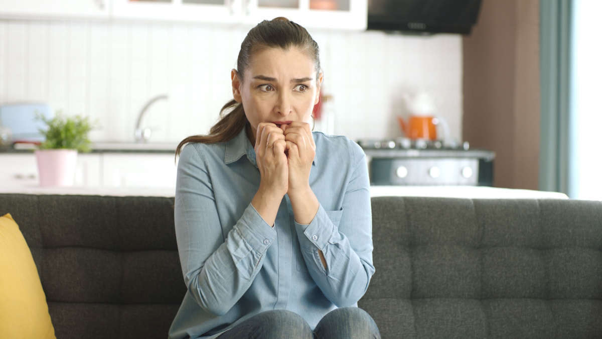 Nervous woman feeling panic, biting her nails, feeling anxious and confused. Frustrated and stressed woman waiting for someone at home. Angry woman biting her nails. Feelings of anxiety, fear.