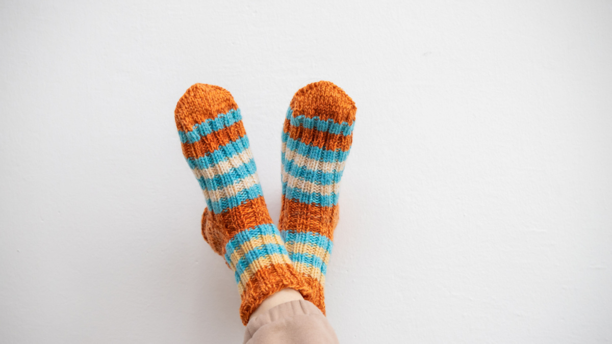 Legs in woolen socks on a white background. Warm socks for winter cold. Handmade knitting.