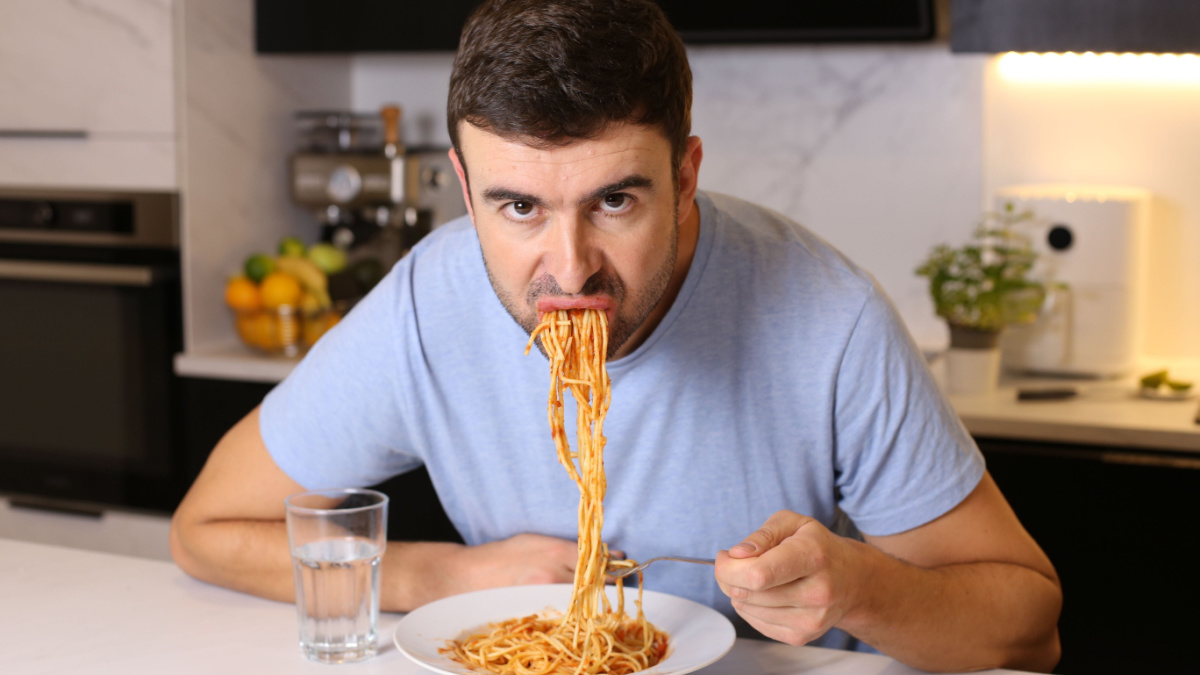 Man eating pasta with bad manners