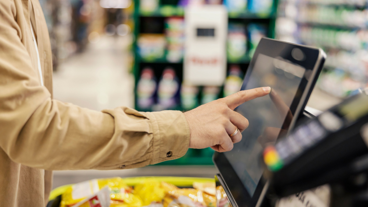 Hand of a man at self-service checkout in supermarket.