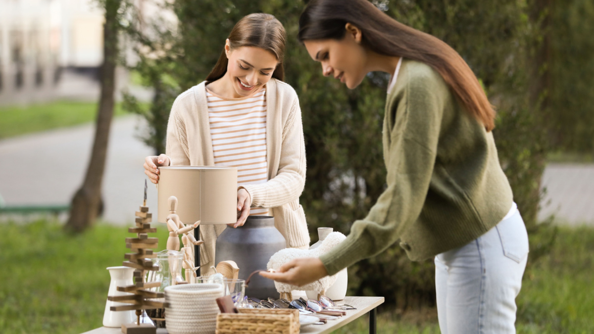 Women shopping at table in yard. Garage sale