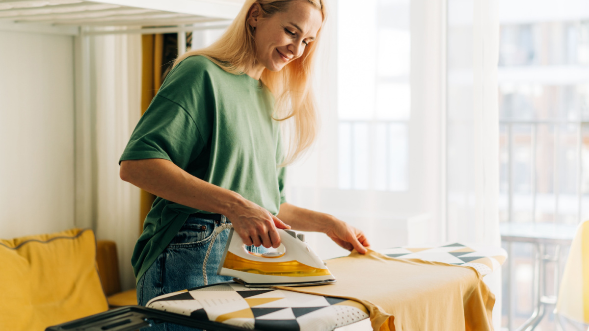 Middle-aged woman housewife ironing clothes at home.