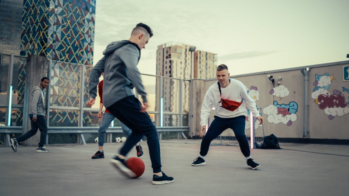 Multiethnic Diverse Friends Playing Soccer Outside on Rooftop Urban City Location. Skilful Young Man Dribbling, Passing Opponents Alone with the Ball and Scoring a Goal