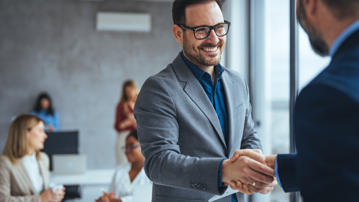 Shot of two businessmen shaking hands in an office. Two smiling businessmen shaking hands while standing in an office. Business people shaking hands, finishing up a meeting