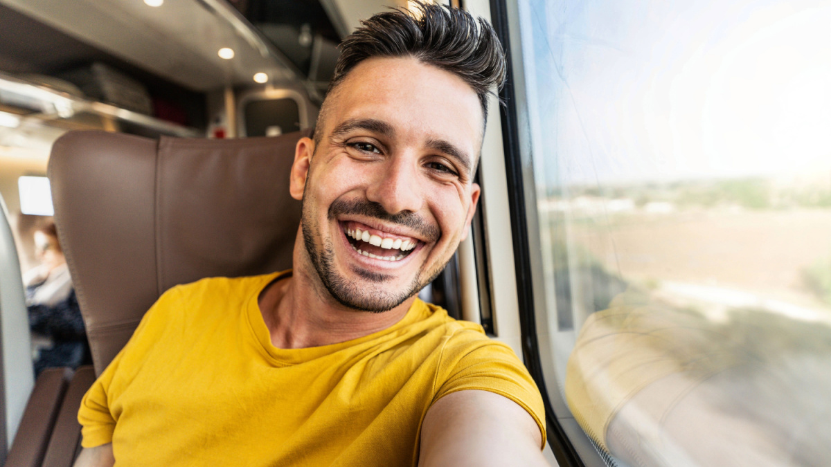 Happy male tourist taking selfie sitting in the train - Transportation, tourism and travel concept.