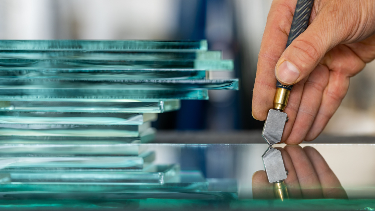 Close-up of a glazier's hand when he cuts glass in a glass factory, Close up, Pieces of thick glass