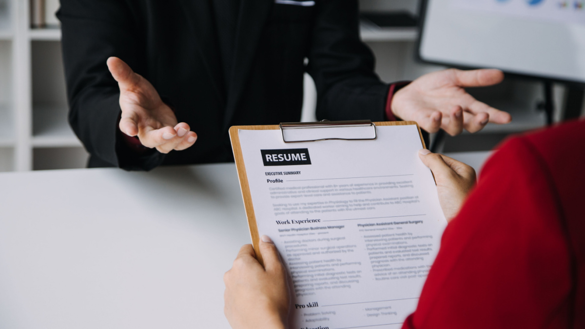 Close up view of job interview in office, focus on resume writing tips, employer reviewing good cv of prepared skilled applicant, recruiter considering application, hr manager making hiring decision.