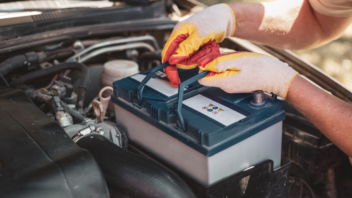 auto mechanic repairs a car. A mechanic removes a car battery from the box.