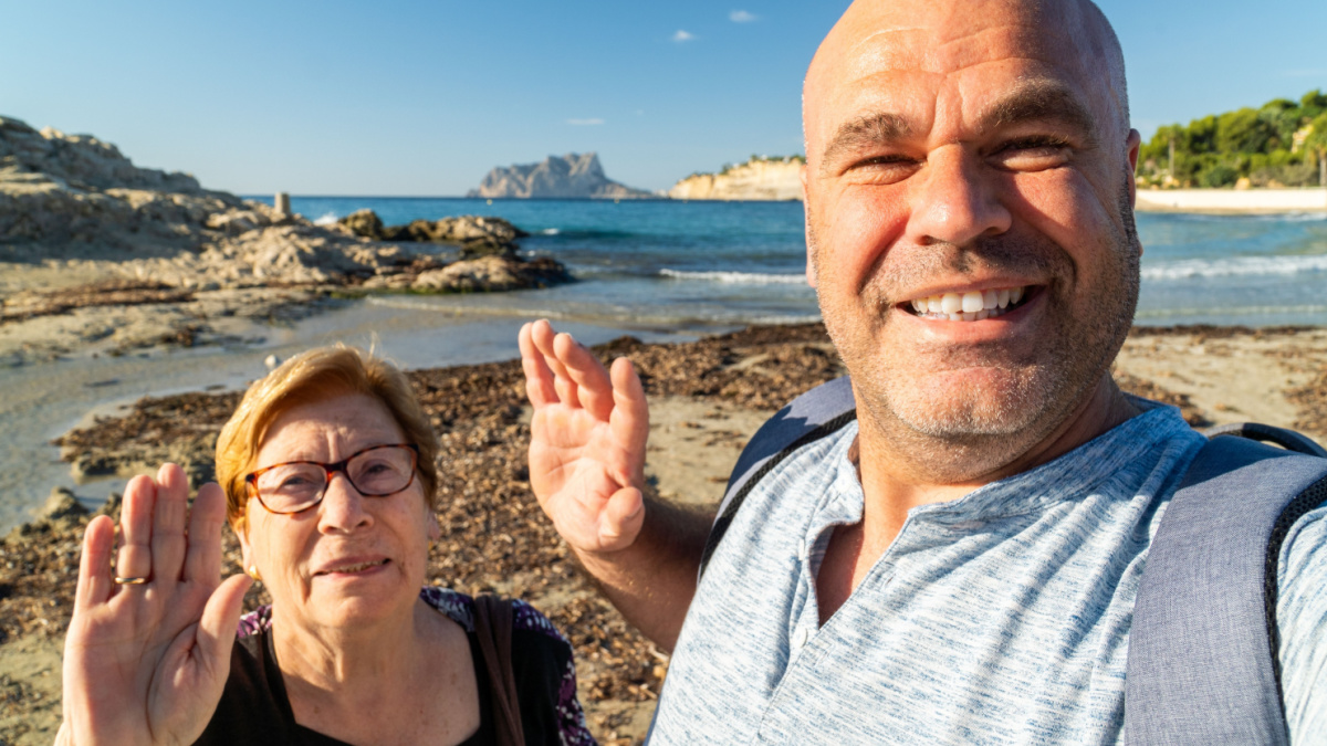 Man with his grandmother takes a selfie enjoying the beach.
