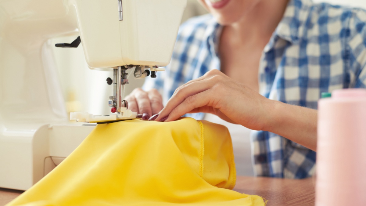 smiley woman sewing on sewing-machine. focus on sewing-machine.