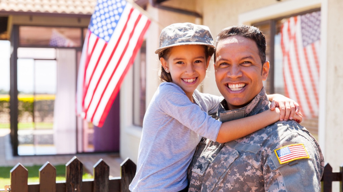 portrait of us army soldier and little daughter outside their home.