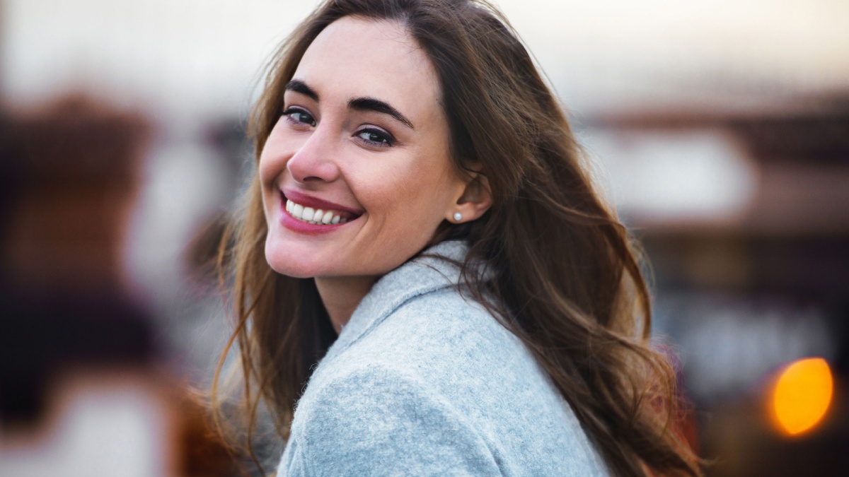 Close-up portrait of beautiful caucasian woman with charming smile walking outdoors.