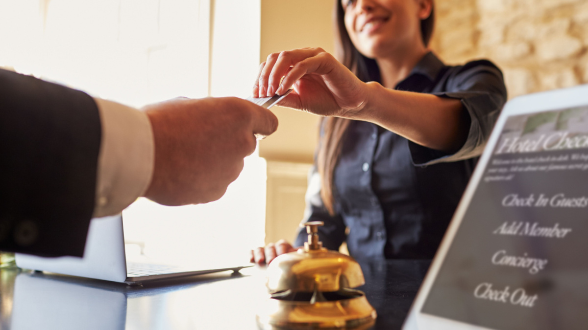 Guest takes room key card at check-in desk of hotel.