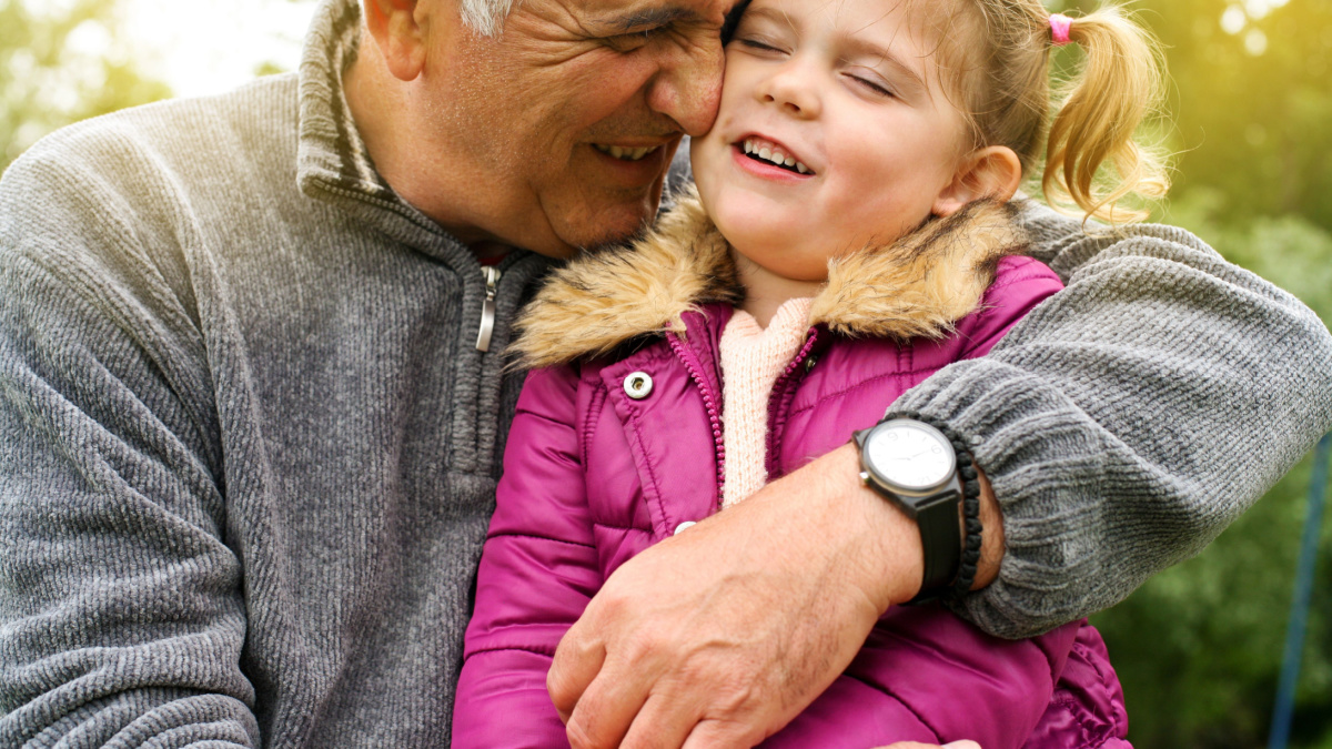Grandfather hugging granddaughter in the park.