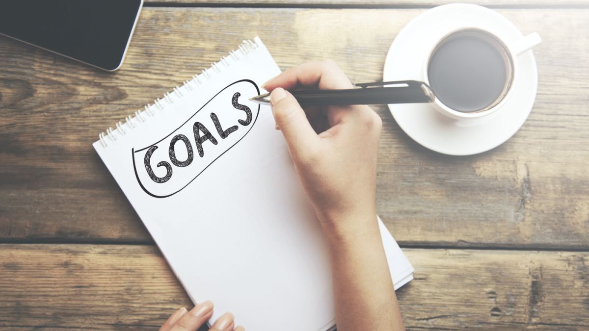 Goals memo written on a notebook with woman hand pen.