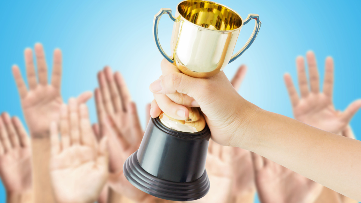 Winner of voting,Hand holding Trophy cup on hands raised in the air over blue background.