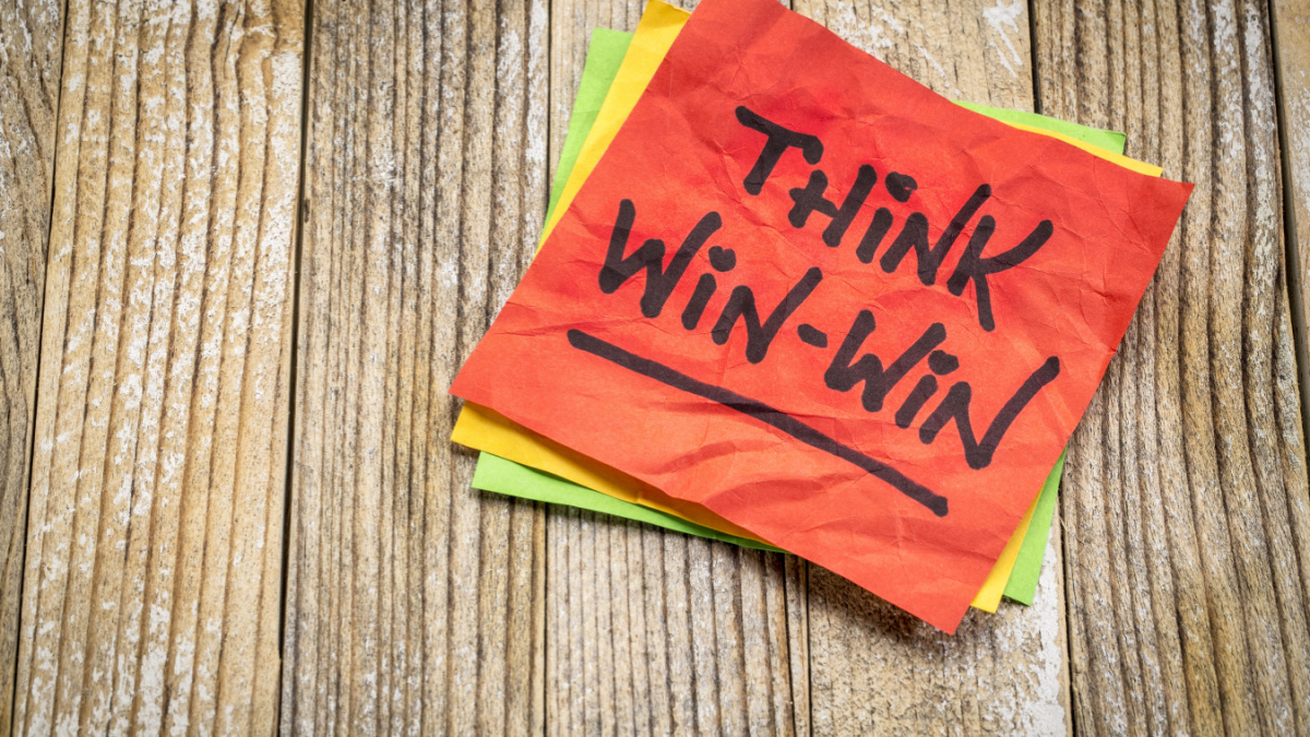 Think win-win concept - handwriting on a sticky note against grunge wood board.