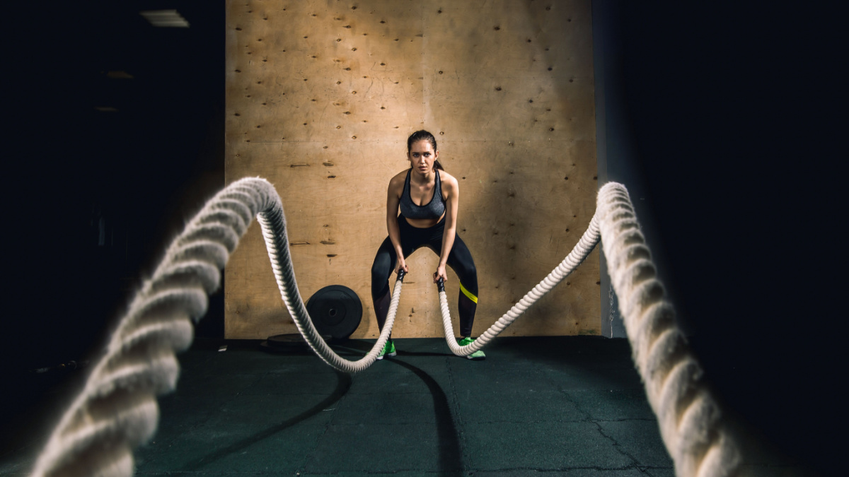 Athletic young woman doing some crossfit exercises with a rope outdoor