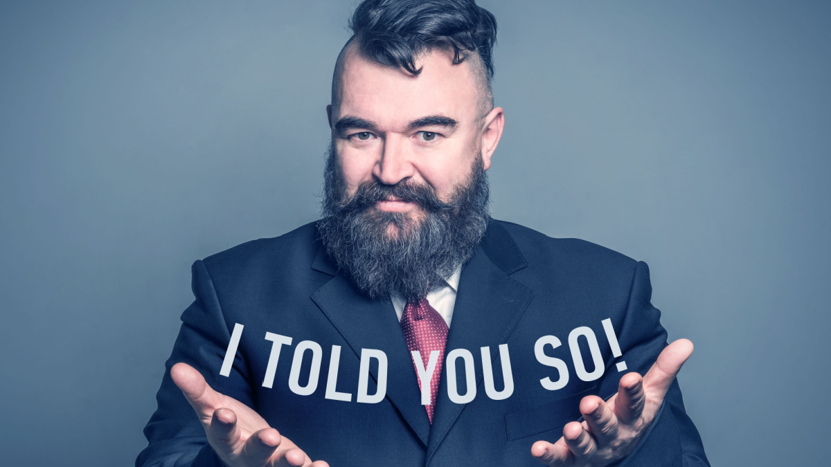 Adult bearded man in a suit holding the inscription I TOLD YOU SO.