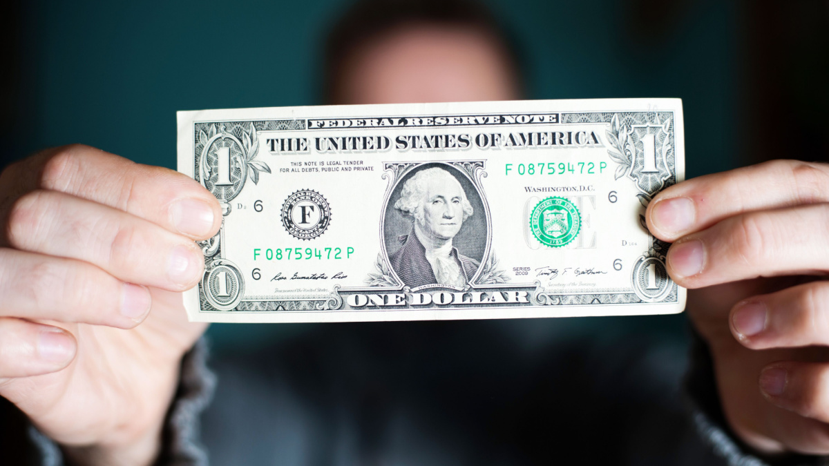 A man holds a U.S. 1 one dollar.