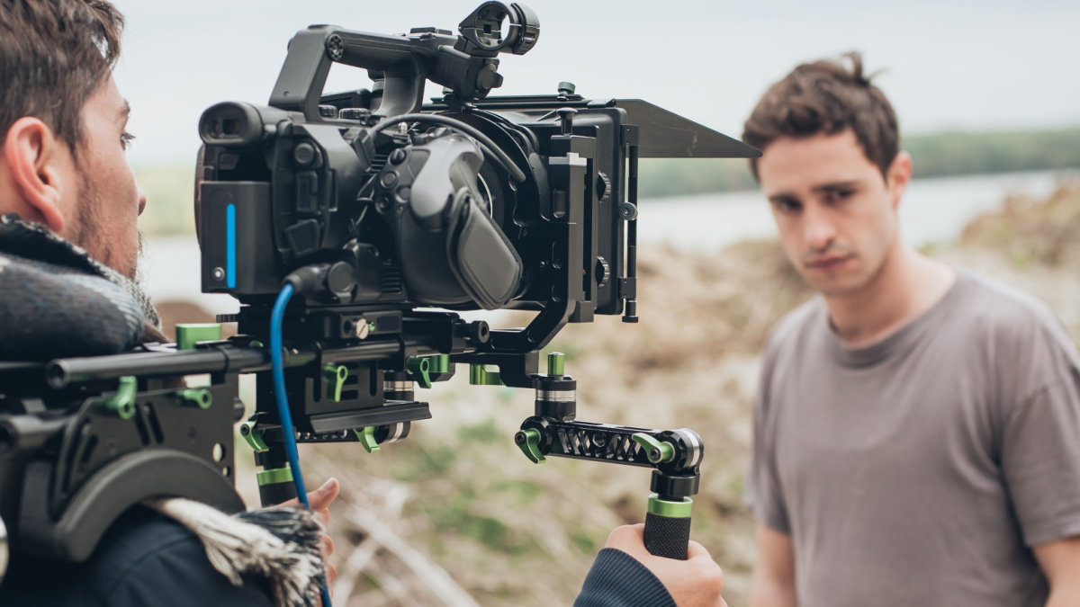 Behind the scene. Actor in front of the camera on the film set outdoor location. Group movie scene.