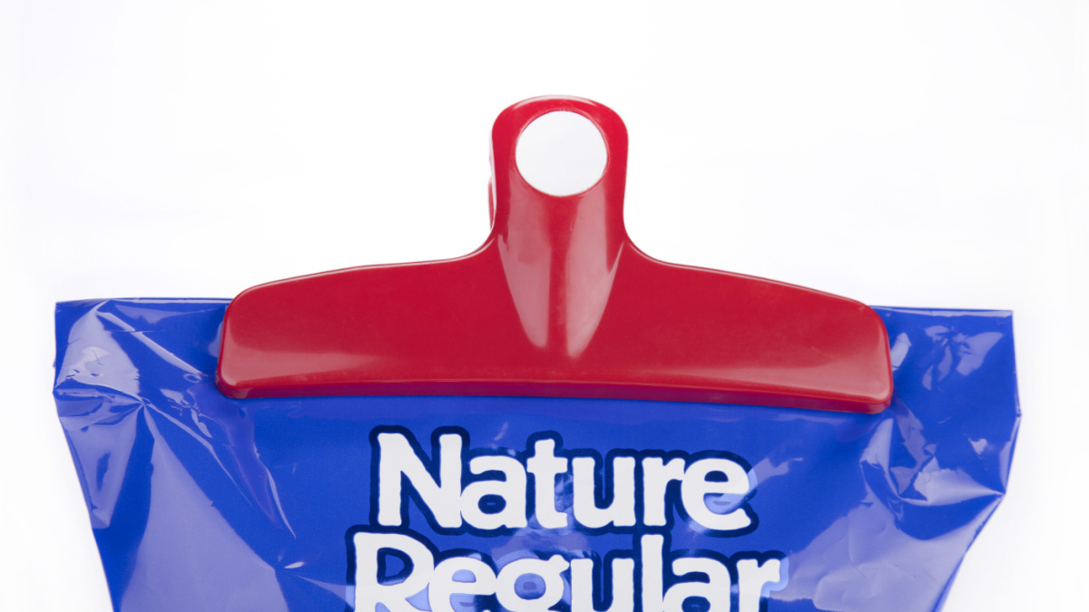Red plastic chips bag clip on a blue bag of chips. Bag clip and chips