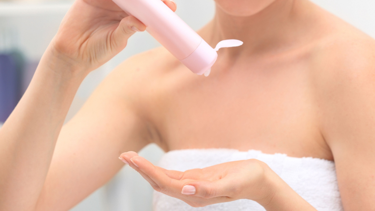 Young woman with bottle of cosmetic product in bathroom