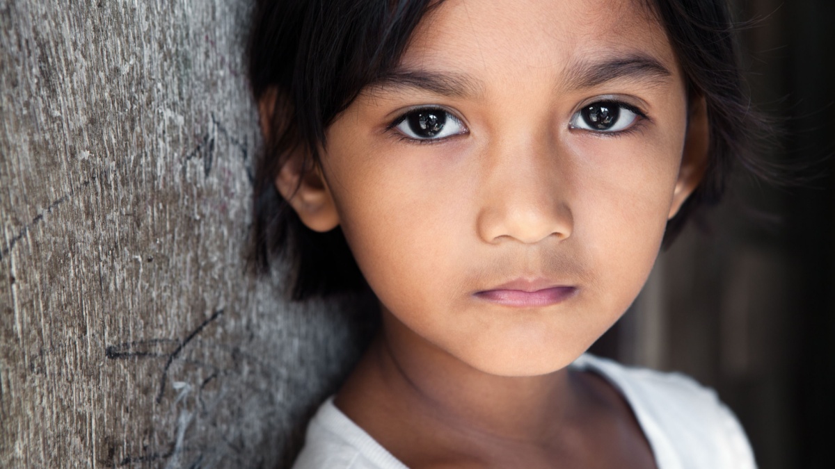 Portrait of a pretty 8 year old Filipina girl in poverty-stricken neighborhood, natural light.