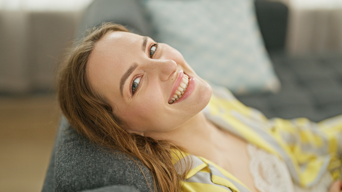 Young blonde woman relaxed on sofa smiling at home.