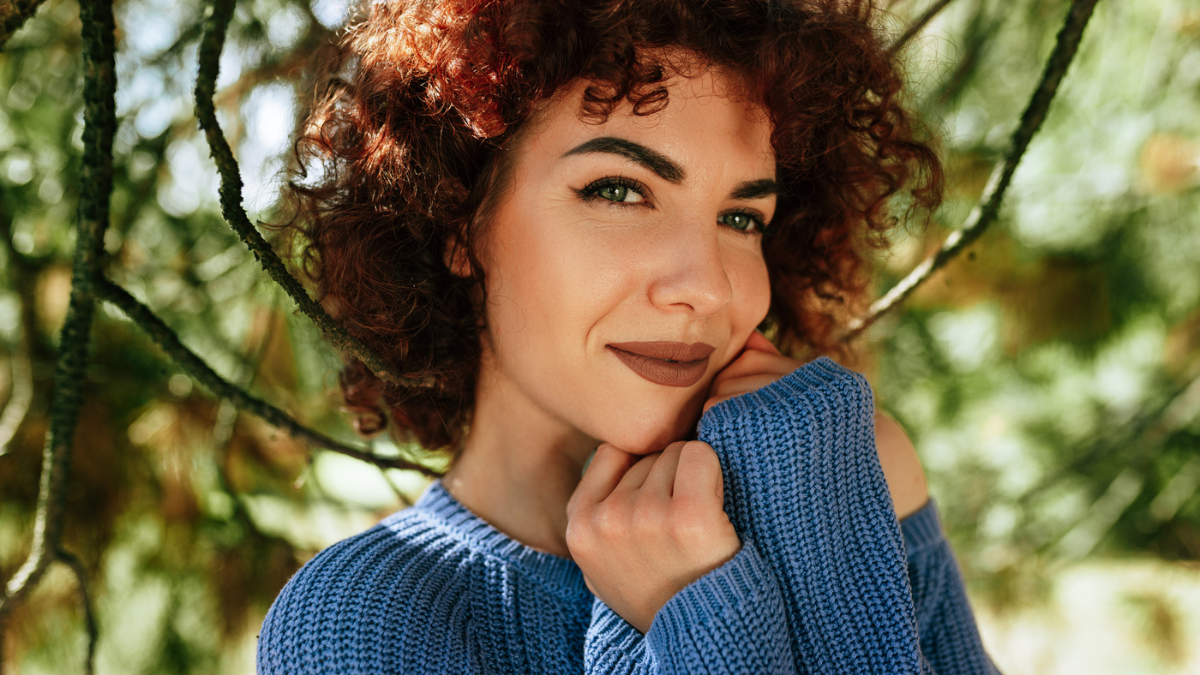 Outdoor close-up portrait of gorgeous young woman with curly hair.