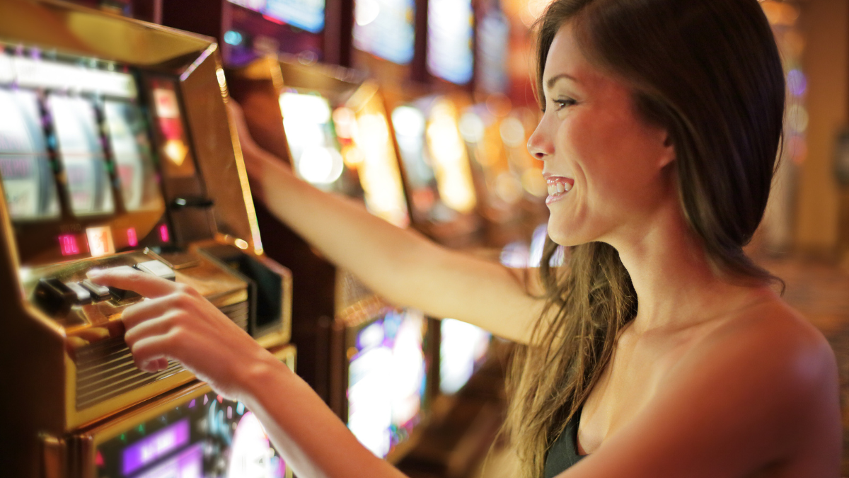 Asian woman gambling in casino playing on slot machines.