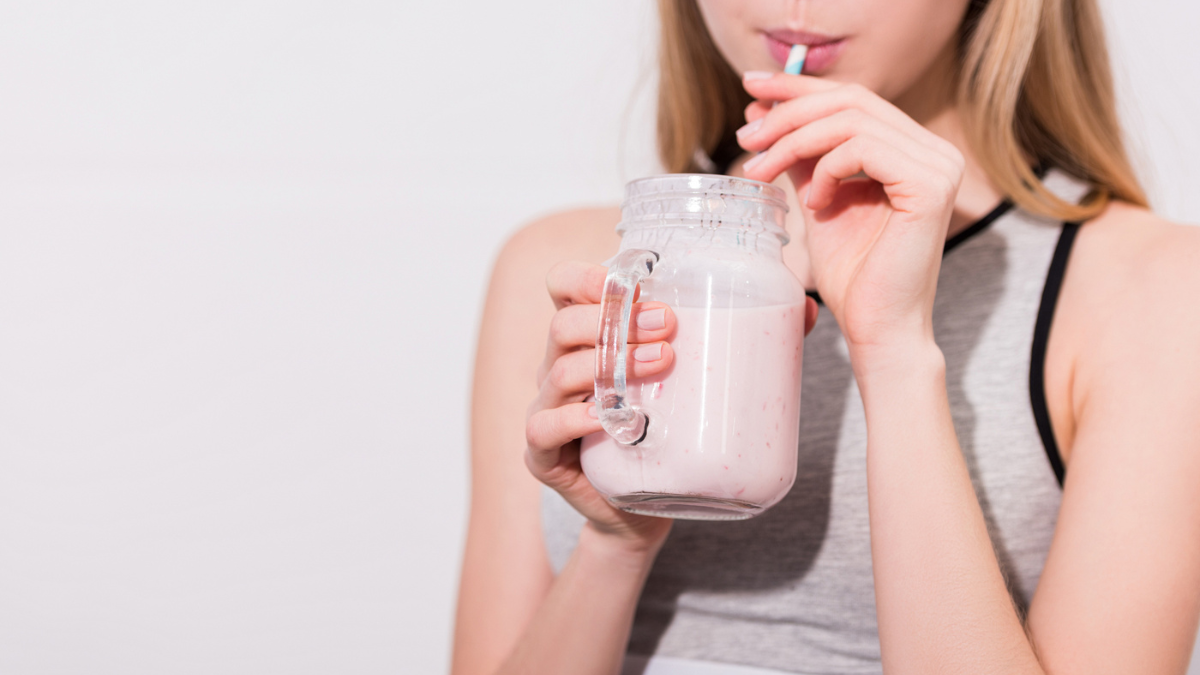 woman drinking smoothie in mason jar.
