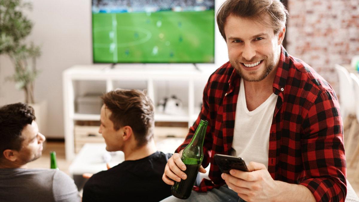 Football fans with mobile phone and beer.