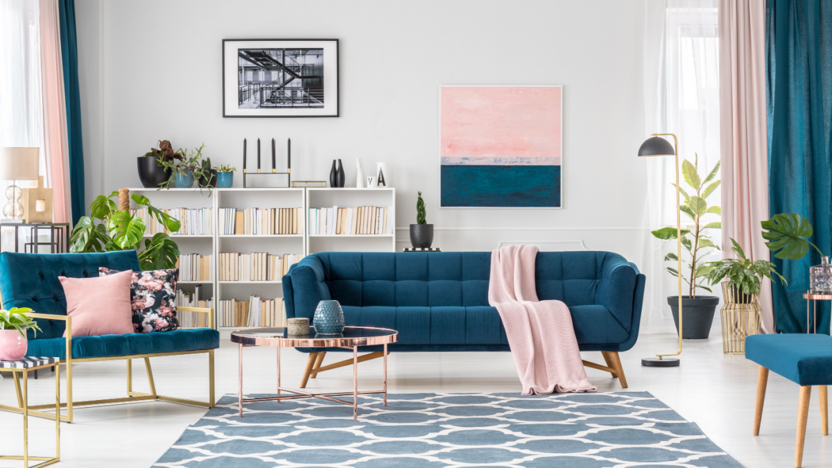 Patterned carpet in pink and blue living room interior with sofa against white wall with painting