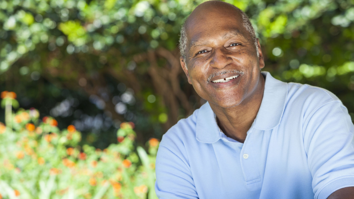 A happy senior African American man in his sixties outside smiling.