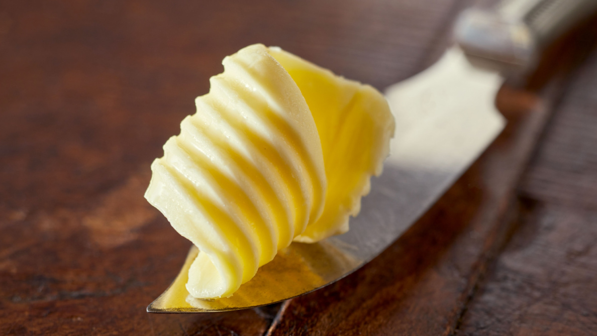8 Products Frugal People Always Buy In Bulk 7 Elegant swirl or curl of fresh farm butter displayed on a silver vintage butter knife in a close up view