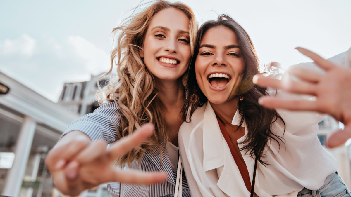 Lovable caucasian girls expressing positive emotions to camera. Outdoor photo of refined sisters posing on sky background.